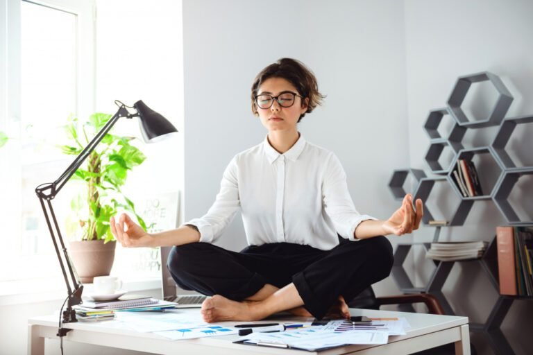 mulher sentada em mesa de escritório representando o equilibrio entre vida pessoal e trabalho